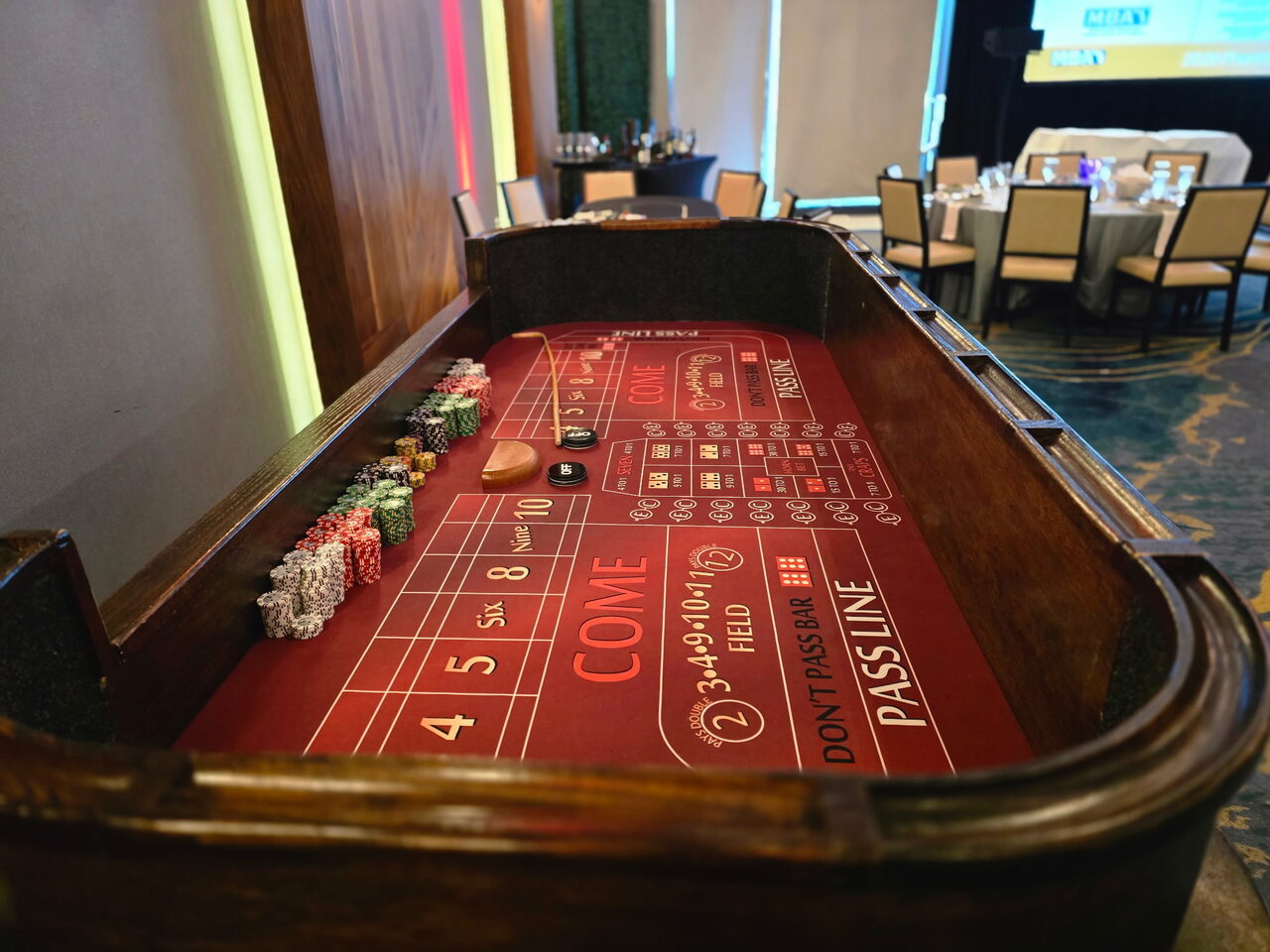 Red-felt craps table with a chip rail at a Sacramento corporate casino night