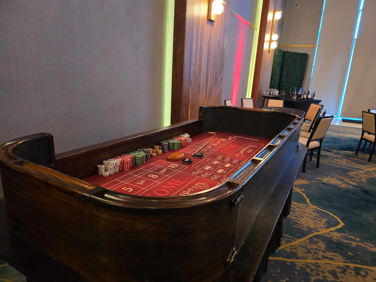 Red-felt craps table in a modern neon-lit Sacramento event space